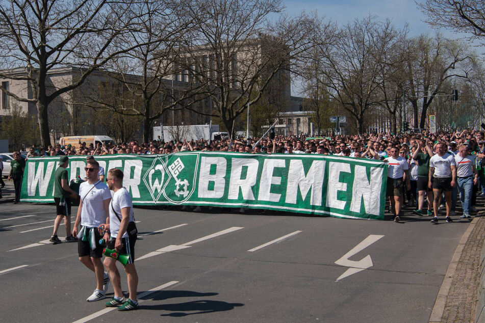 Die Werder-Schar trägt auf dem Weg ins Stadion ein großes Vereinsbanner vor sich her.