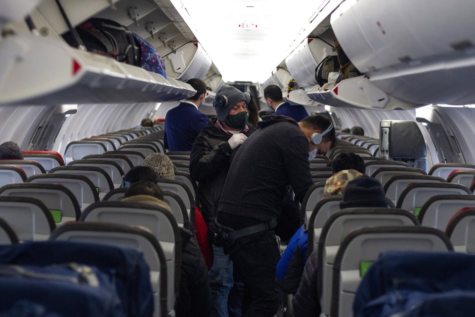 Passagiere mit Mundschutz steigen in ein Flugzeug.