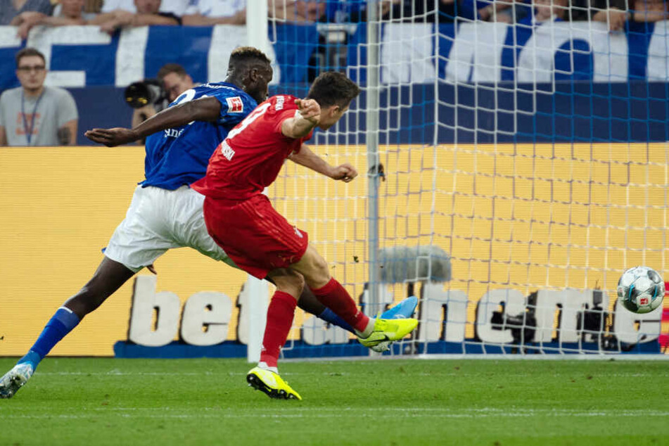 Schalkes Salif Sane (l) kann Bayerns Robert Lewandowski nicht davon abhalten, das 3:0 zu erzielen.