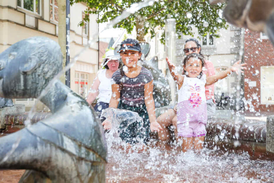 In einem Brunnen in Lingen kühlen sich Kinder und Erwachsene ab.