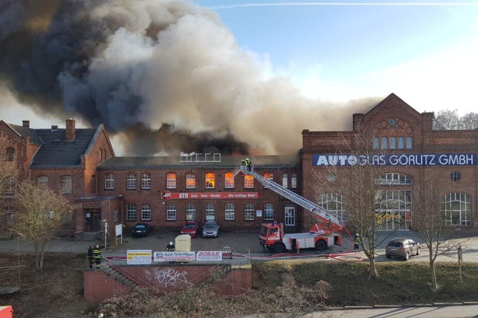 Feuerwehrleute löschen von der Drehleiter aus das Feuer.