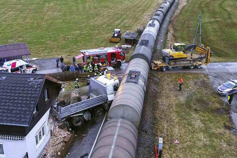 Der Hänger mit dem Bagger steht noch auf der Straße, der Kipplaster wurde in das Haus geschoben und beschädigte es schwer.