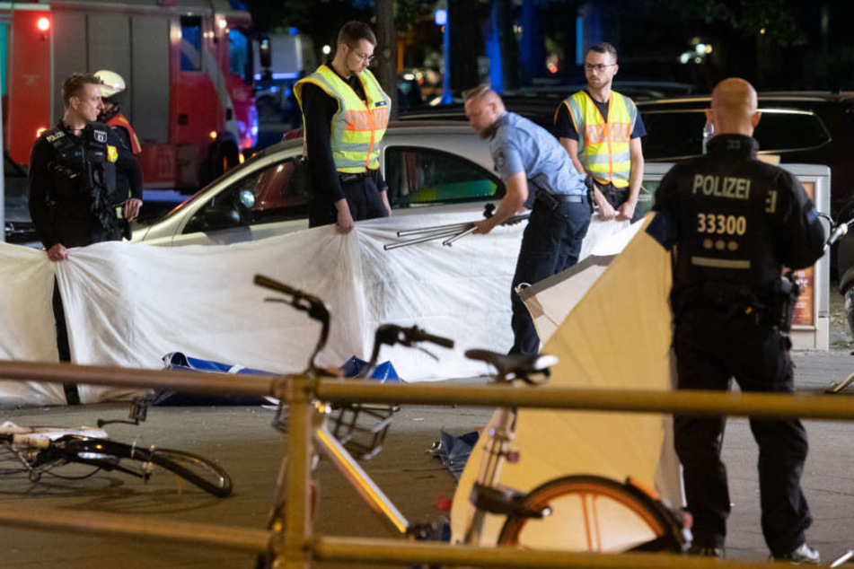 Polizeibeamte schirmen die tödlich verletzte Frau mit Decken ab.