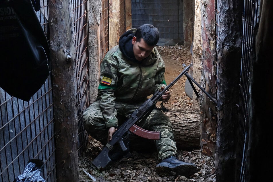 Ein kolumbianischer Söldner, der auf Seiten der Ukraine kämpft, überprüft seine Waffe.