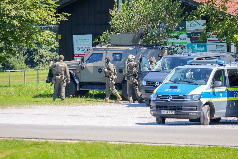 Sondereinsatzkräfte besprechen sich an einem Bauernhof in Seeg.