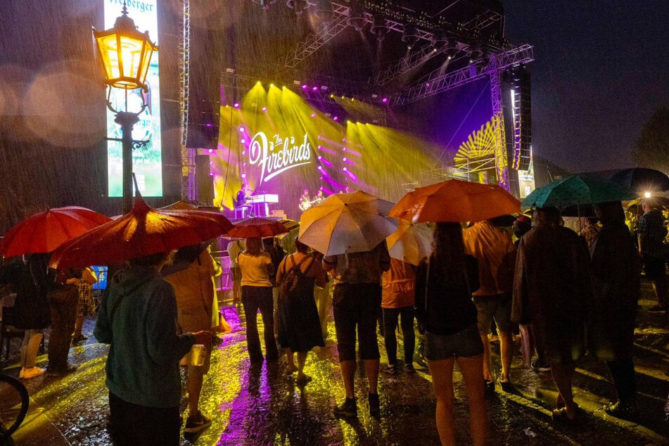 Trotz des starken Regens lauschen zahlreiche Zuhörer dem Konzert auf dem Theaterplatz.