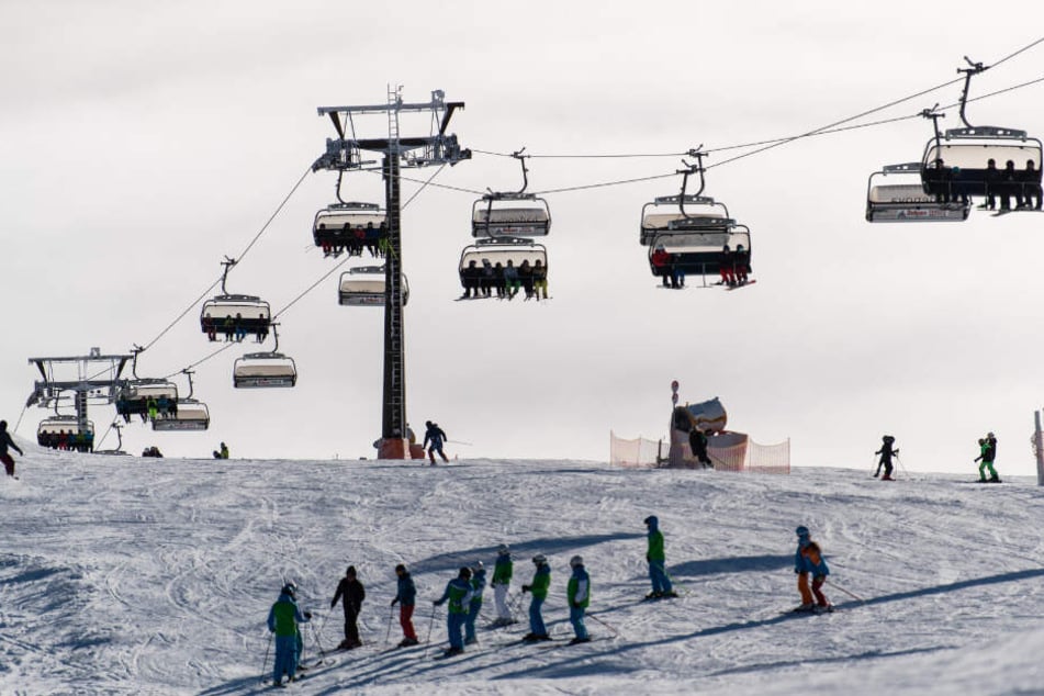Unter einem Skilift fahren Menschen Ski. (Symbolbild)