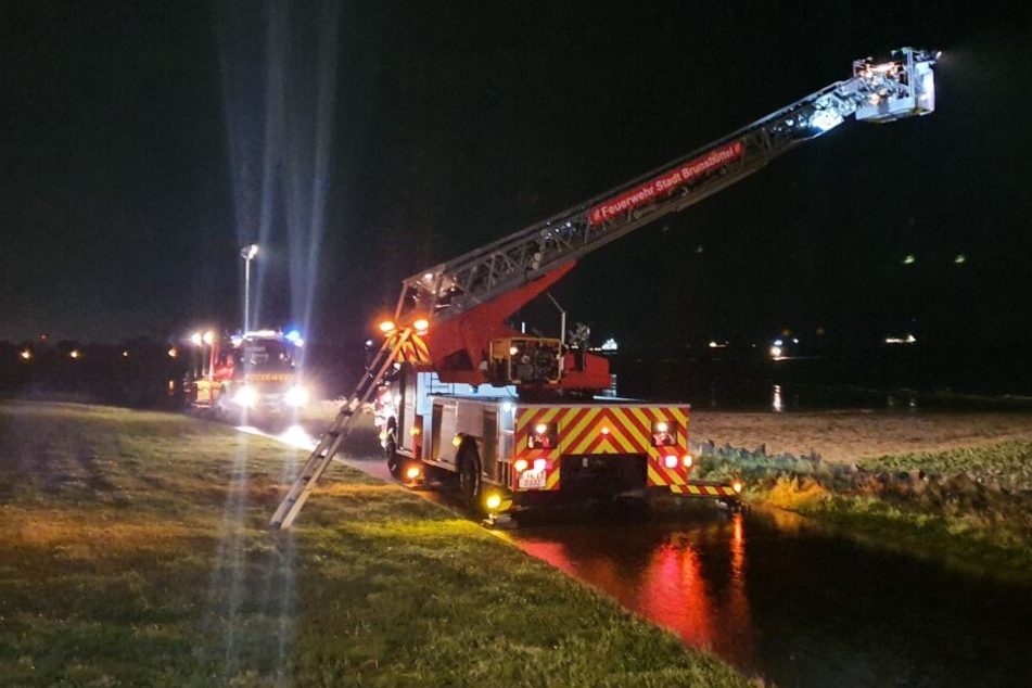 Feuerwehrfahrzeuge stehen an einem Deich bei Brunsbüttel.