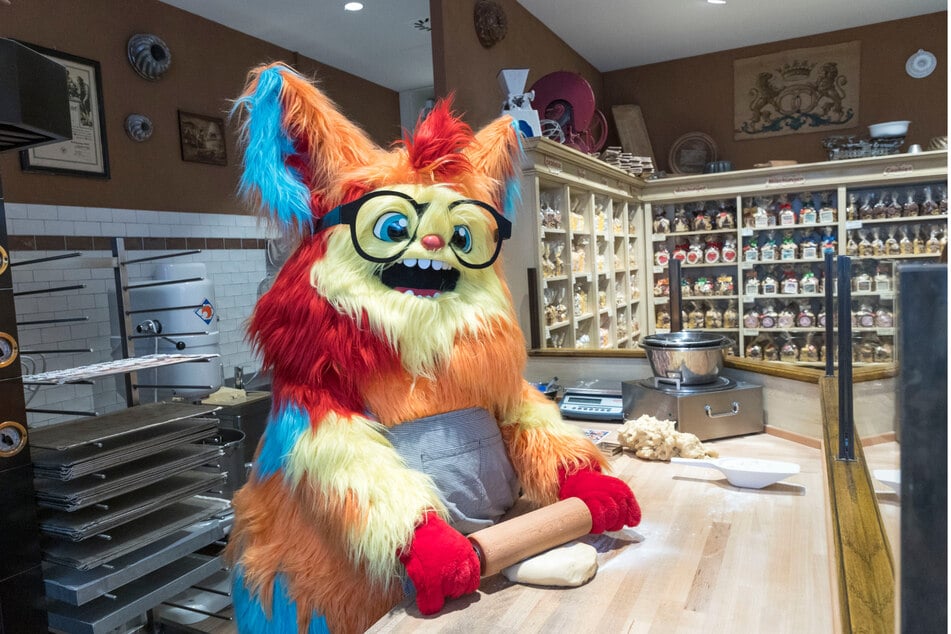 Messe-Maskottchen Keks rollt in der Kexerei im Kaufpark Nickern einen Keksteig aus.