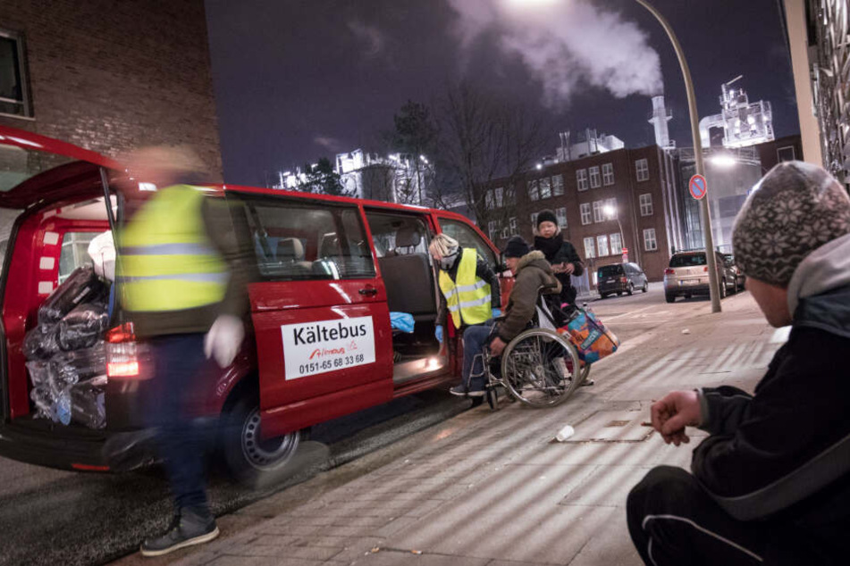 Die freiwilligen Helfer helfen Menschen mit Rollstuhl, die auf der Straße leben, in den Kältebus.