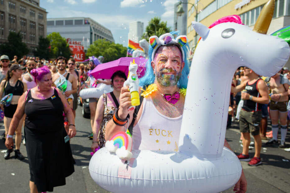 Ein CSD-Teilnehmer läuft mit einem aufblasbaren Einhorn durch Berlin