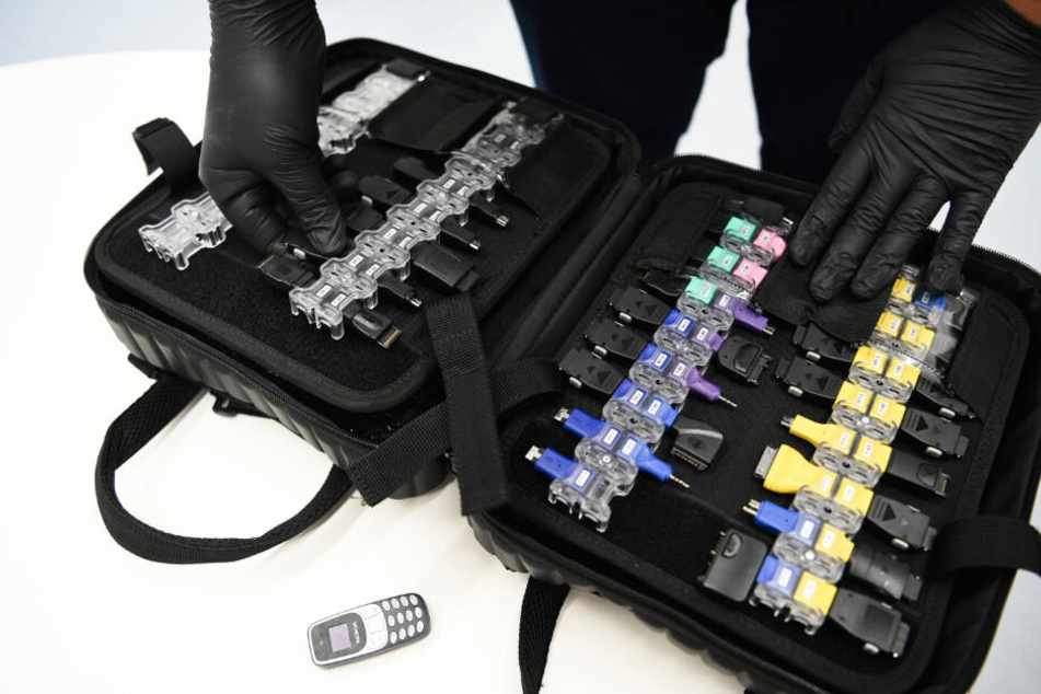 Ein IT-Forensiker zeigt einen Koffer, in dem Kabel für nahezu jeden Smartphone- Anschluss sind.