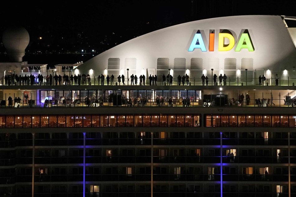 Menschen stehen auf dem Deck des deutschen Kreuzfahrtschiffs "Aida Nova", das am Silvesterabend kurz vor Mitternacht in Lissabon angelegt hat.