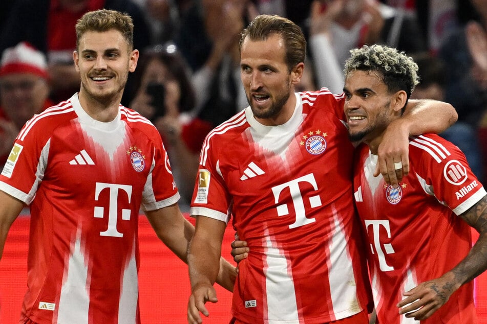 Sportlich hui, in Sachen Kleidung – nicht nur laut Ultras – eher Pfui: Harry Kane (M.) feiert mit Josip Stanisic (l.) und Luis Diaz den fünften Bayern-Treffer zu Saisonauftakt – in den umstrittenen Trikots.