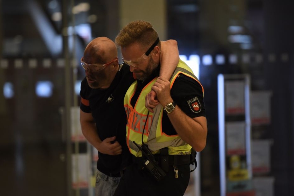 Ein Beamter bringt einen Statisten in Sicherheit.