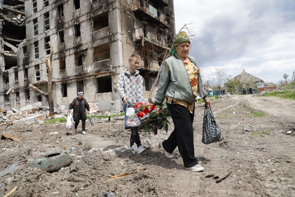 Frauen gehen an einem zerstörten Wohnhaus in der ostukrainischen Hafenstadt Mariupol vorbei.