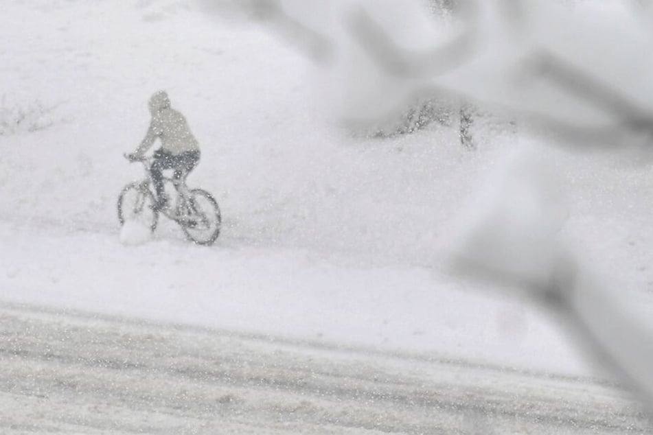 Eine Radfahrerin fährt über eine verschneite Straße in Salzburg.