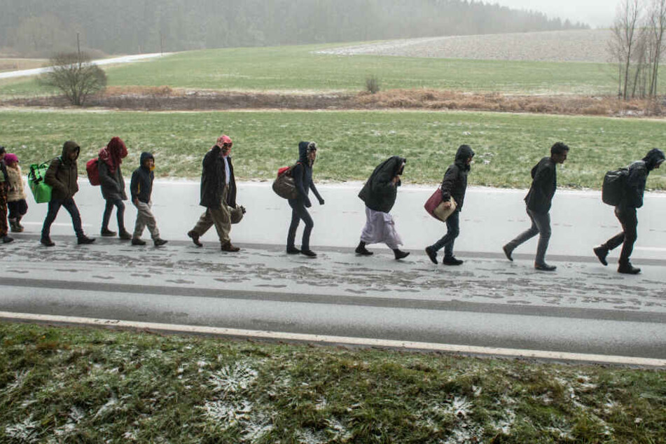 Flüchtlinge gehen an der deutsch-österreichischen Grenze während eines Schneeschauers nach Deutschland. (Archivbild)