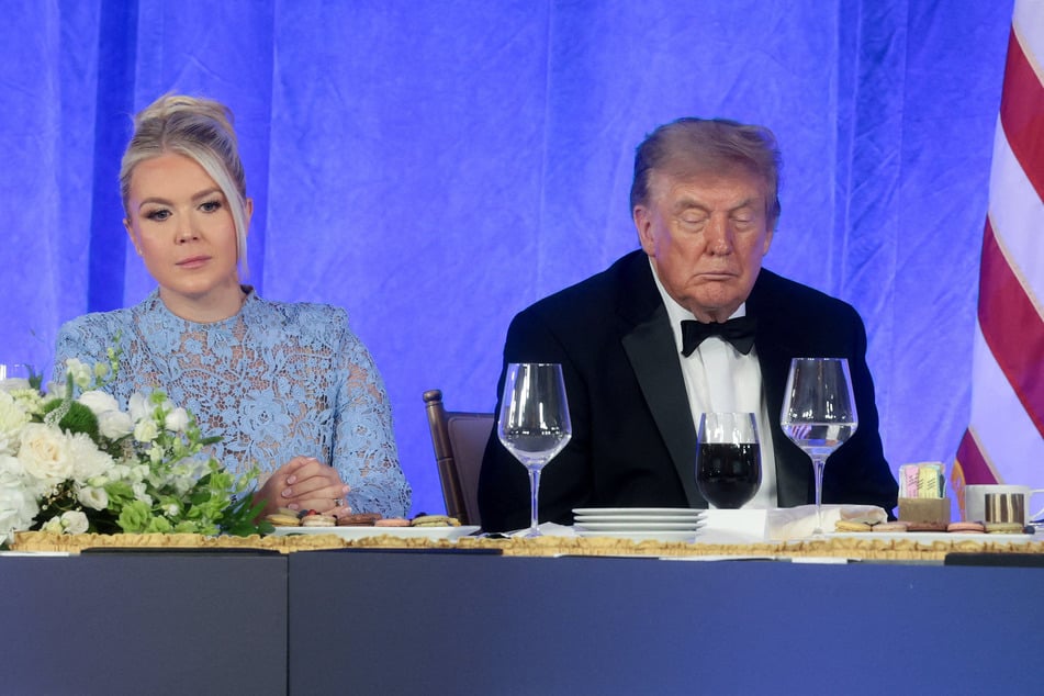 President Donald Trump (r.) and White House Press Secretary Karoline Leavitt (l.) look on as mentalist Oz Pearlman entertains attendees at the White House Correspondents' Association Dinner.