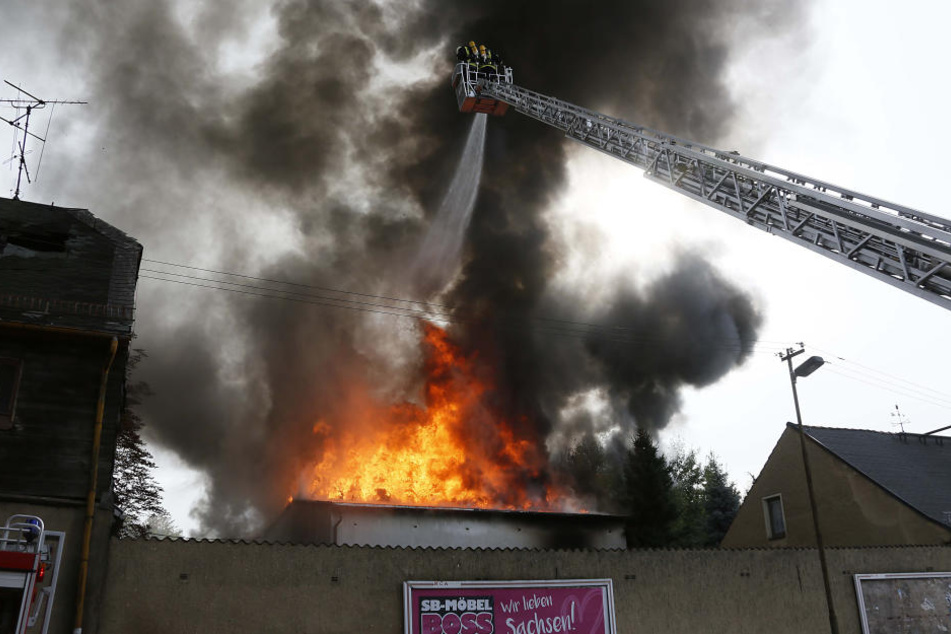 Die Flammen schlagen durch ein Dach.