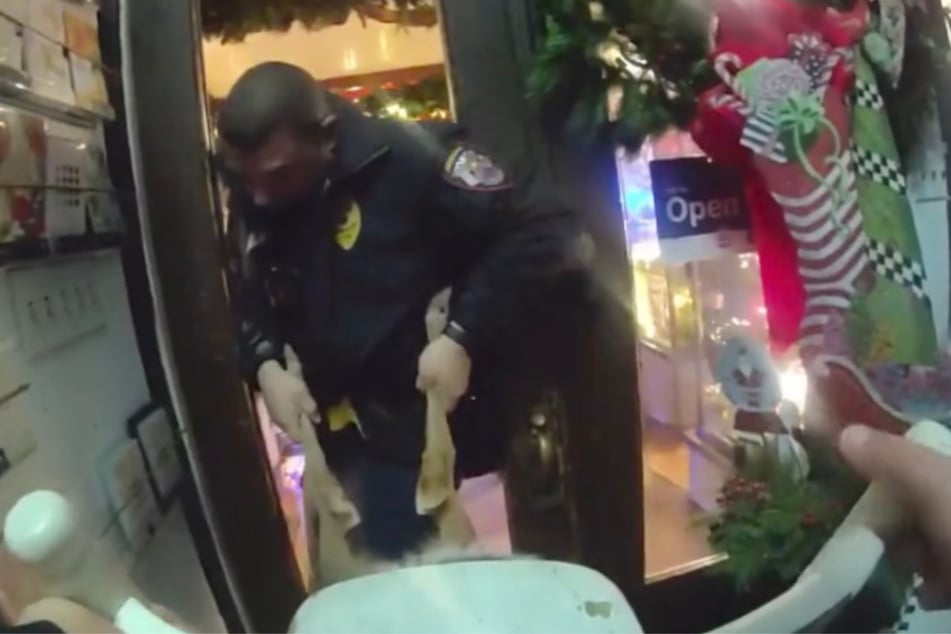 An seinen Hinterläufen bugsiert der Beamte das Rentier aus dem Geschäft.