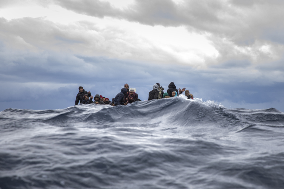 Männer aus Marokko und Bangladesch sitzen in einem überfüllten Holzboot im Mittelmeer vor der Küste von Libyen. (Archivbild)