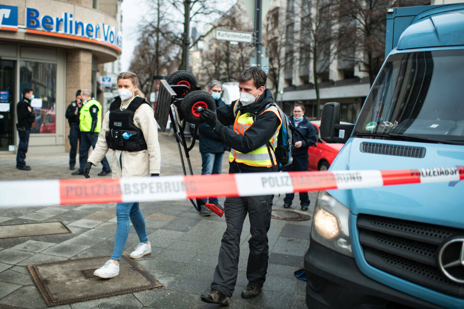 Polizeibeamte sichern Spuren am Tatort. Rechts ist im Anschnitt der überfallene Geldtransporter zu sehen. Gegen einen der mutmaßlichen Räuber beginnt am Donnerstag vor dem Kriminalgericht in Berlin-Moabit der Prozess.