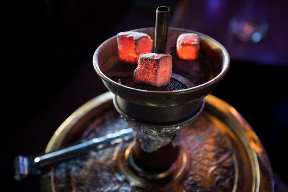 lühende Kohle liegt auf einem Metallsieb über dem Tabak im Kopf einer Wasserpfeife in einer Shisha-Bar.