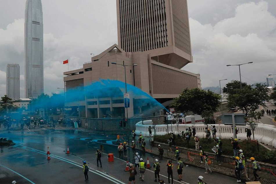 Die Polizei geht mit Wasserwerfern gegen Demonstranten vor und besprüht sie mit blauer Farbe.