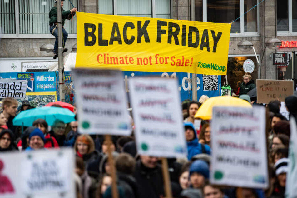 Demonstranten von Fridays for Future hängen am Freitag in Stuttgart ein Plakat mit der Aufschrift "Black Friday, Climate not for Sale!" auf.