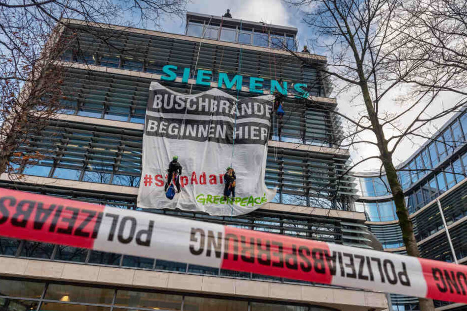 Aktivisten von Greenpeace hängen an der Fassade der Siemens-Zentrale vor einem Transparent mit der Aufschrift "Buschbrände beginnen hier! - #StopAdani".