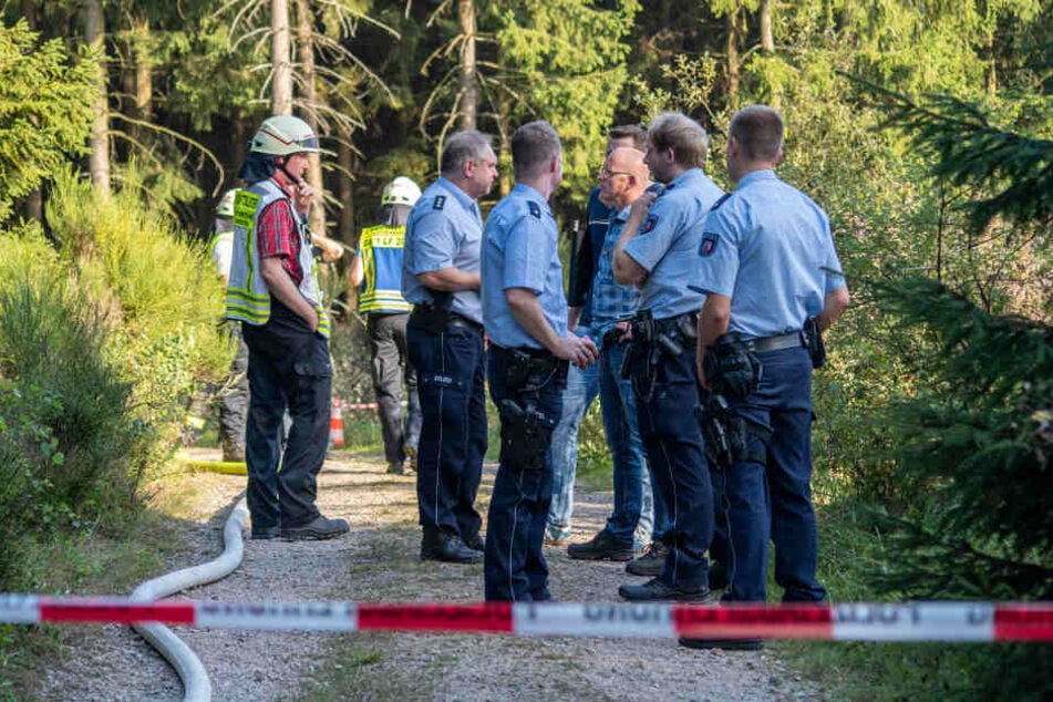 Feuerwehrleute und Polizisten stehen in einem Waldstück auf dem Gebiet von Plettenberg/NRW.