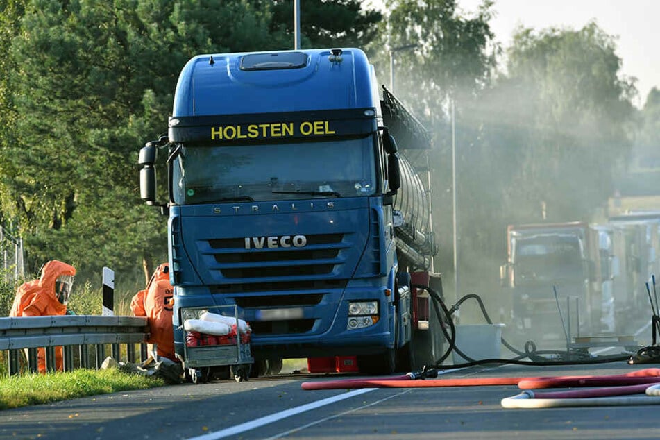 Feuerwehrleute in Schutzanzügen arbeiten am leckgeschlagenen Lkw, der mit 11.000 Liter Salpetersäure beladen war.