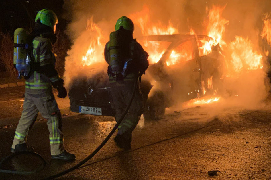 Feuerwehrleute löschen den brennenden Renault in Berlin-Lichtenberg.
