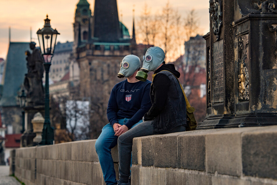 Ein Paar mit Gasmasken sitzt auf der Karlsbrücke in Prag.