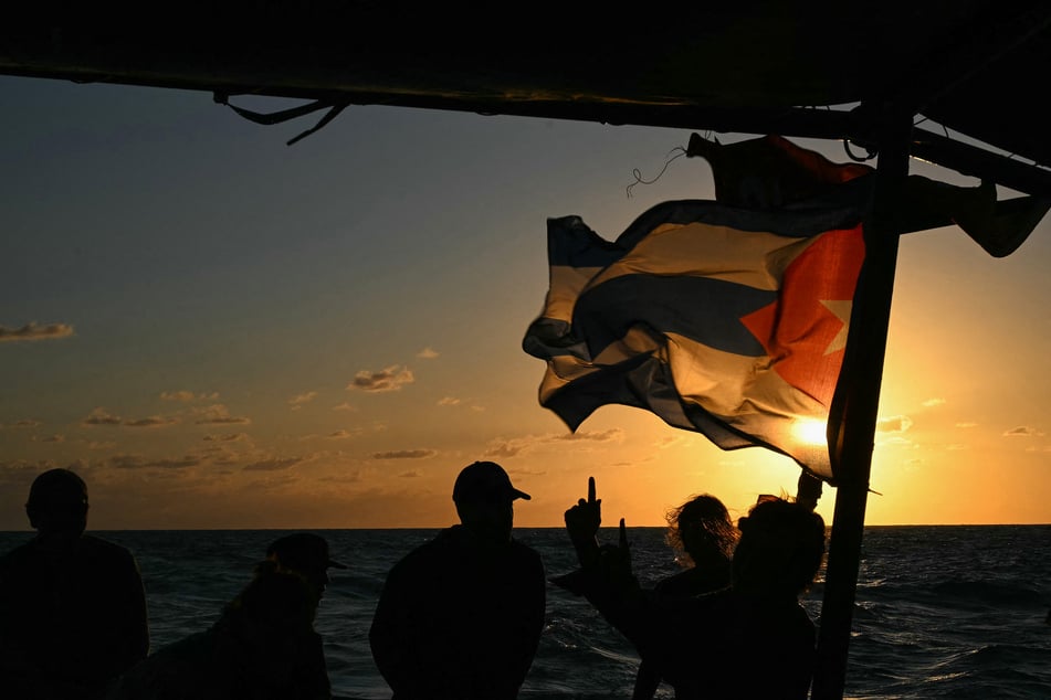 Silhouettes of activists and a Cuban flag are seen aboard the Grandma 2 in the Caribbean Sea on March 20, 2026.