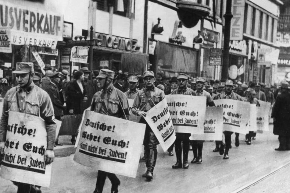 "Deutsche wehrt Euch! Kauft nicht bei Juden!" steht auf den Schildern, die Männer der SA bei einem Hetzmarsch gegen Juden durch die Straßen Berlins tragen.