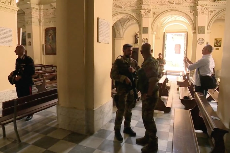 When journalists in Italy visit a 'Ndrangheta church, they are protected by Carabinieri forces armed with submachine guns.