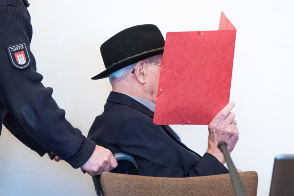 Der angeklagte, ehemalige SS-Wachmann versteckt sein Gericht hinter einer roten Mappe.
