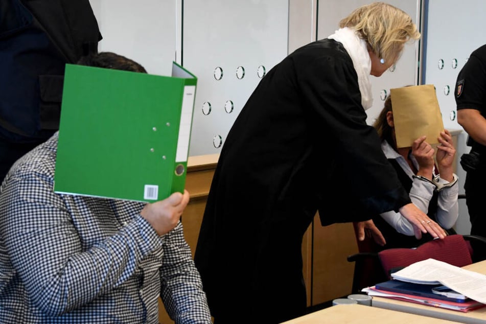 Mit verdeckten Gesichtern sitzen die Angeklagten zum Auftakt des Mordprozesses im Gerichtssaal.