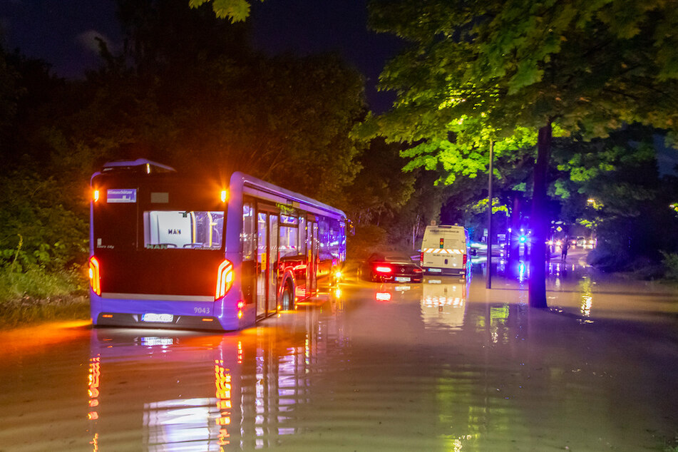 Ein Bus, ein Transporter sowie ein Auto blieben auf einer überfluteten Straße in München stecken.