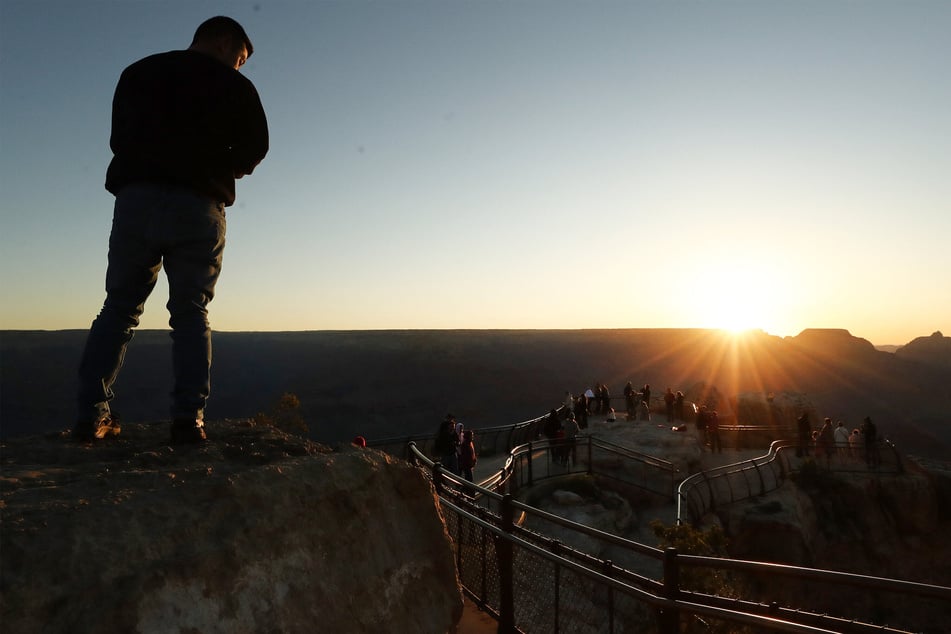 Visitors watch the sunrise from the South Rim of Grand Canyon National Park in Arizona, one of the most popular National Parks.