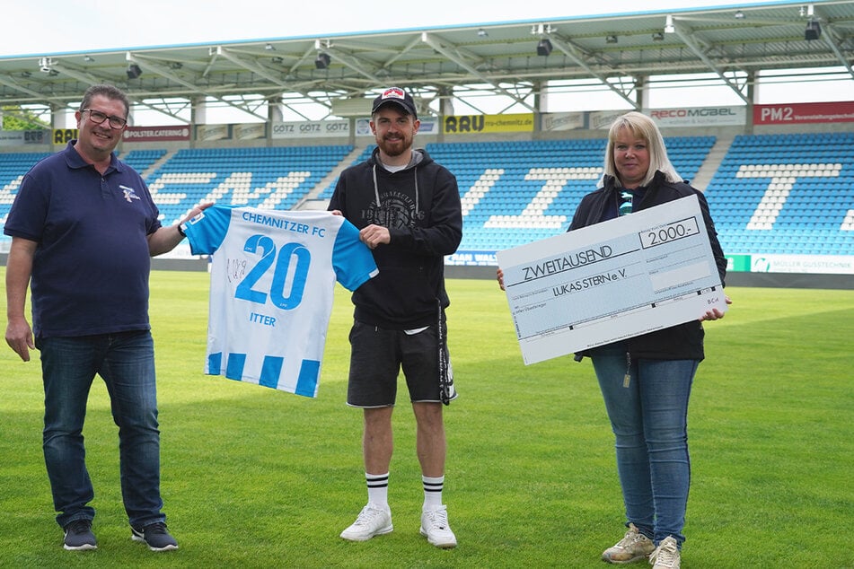 Daniela Lieberwirth (r.) und Christian Frank (l.) vom Lukas Stern e.V. nahmen von Pascal Itter den symbolischen 2000-Euro-Scheck entgegen. Der Trikot-Ersteigerer wollte nicht aufs Foto und lieber anonym bleiben.