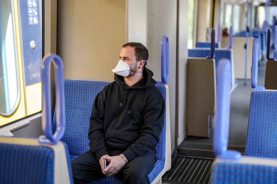 Ein junger Mann trägt in einer Stadtbahn eine Atemschutzmaske der Kategorie FFP2.