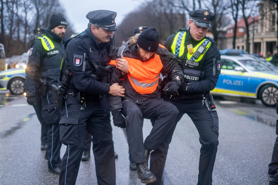 Polizisten tragen einen der Demonstranten von der Straße.