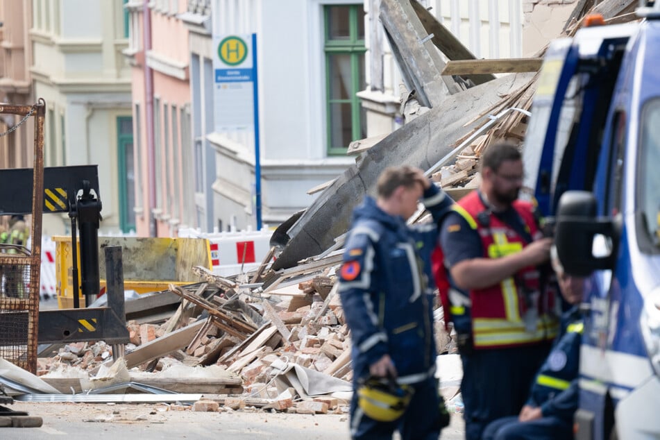 Einsatzkräfte des Technischen Hilfswerks (THW) stehen vor dem Schuttberg des eingestürzten Wohnhauses in der Innenstadt.