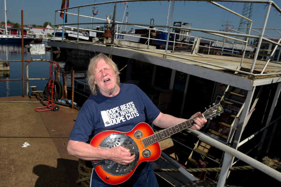 Gunter Gabriel spielt im Hafen vor seinem Hausboot Gitarre. Jahrelang lebte der Country-Sänger auf seinem Hausboot im Harburger Binnenhafen. (Archivbild).