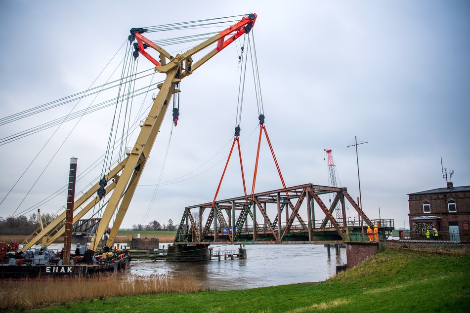 Ein Teil der Friesenbrücke wird mithilfe eines Schwimmkrans abgebaut.