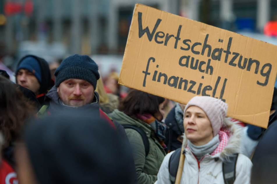ErzieherInnen und LehrerInnen stehen während eines Warnstreiks mit einem Schild "Wertschätzung auch finanziell" auf dem Dorothee-Schlegel-Platz, um für faire Löhne und bessere Arbeitsbedingungen zu demonstrieren.