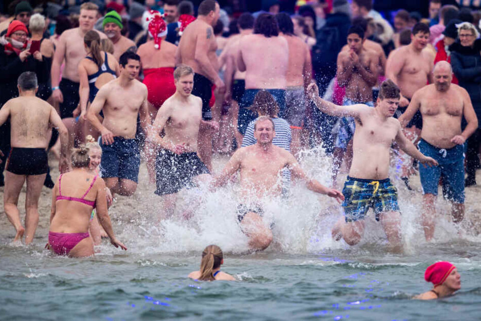 Schwimmer laufen beim Anbaden am Neujahrstag ins eiskalte Wasser.